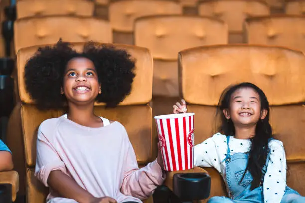 Happy and funny kid with popcorn watch cinema in movie theater
