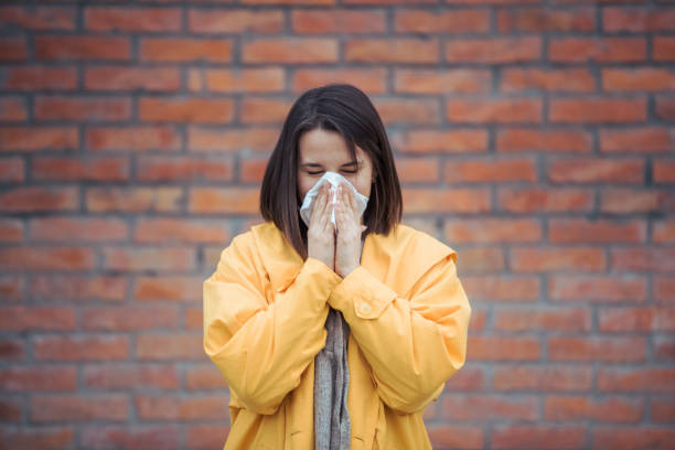 istock Sick young woman blowing her nose 1209474538