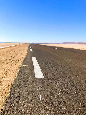 Sign on asphalt street through Chott el Djerid, salt lake, on a sunny day with clear sky, Tunisia