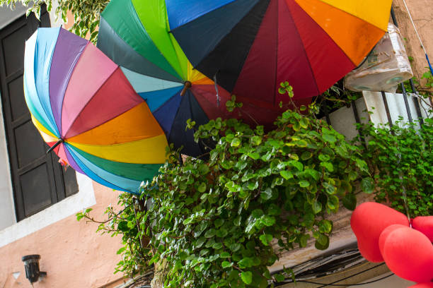 gli ombrelloni aperti in colore della comunità lgbt sul balcone della città vecchia in segno di vicinato amichevole e ospitalità per tutti i tipi di persone di genere. da qualche parte nella città vecchia della spagna, in europa. - gay pride wristband rainbow lgbt foto e immagini stock