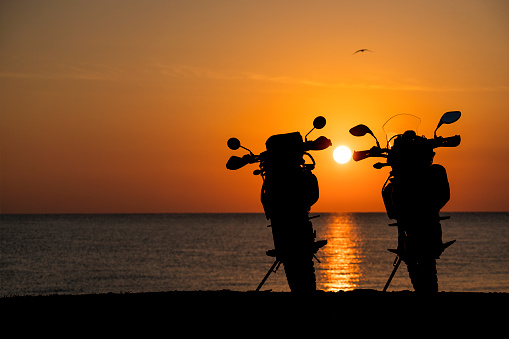 Silhouette of enduro motorcycles on the beach ant sunrise