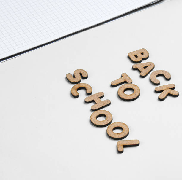 istock School time minimal concept. Notepad, autumn fallen leaves on white background with slogan back to school from wooden letters. 1209483909