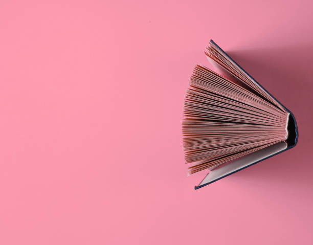 istock Open old book on pink background. Top view, minimalism 1209483998