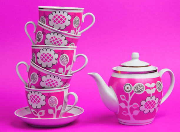 istock Stack of retro ceramic cups and teapot on pink background. Top view 1209484023