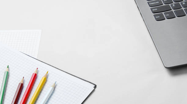 istock Back to school minimalistic concept. Laptop, color pencils, notebook on white background. Slogan school time with wooden letters 1209484099