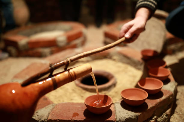 Person pouring wine from qvevri using Orshimo Person pouring wine from qvevri using Orshimo, Georgia kakheti georgia stock pictures, royalty-free photos & images