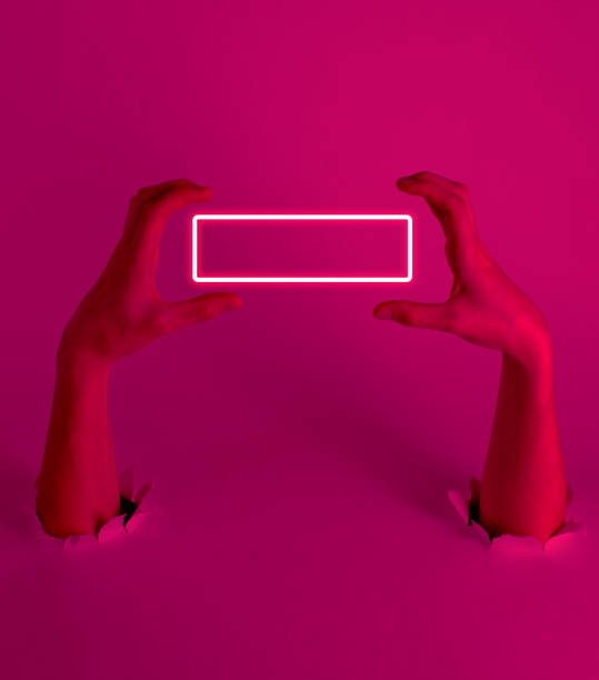 istock Female hands through the torn holes with pink light. Neon frame. Copy space. Creative art 1209487345