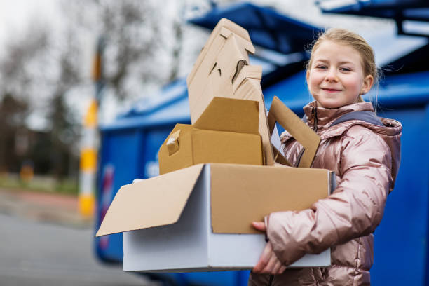 Young girl at a paper recycling centre A beautiful dutch girl recycling paper at a neighbourhood environmental recycling centre in the daytime recycling center stock pictures, royalty-free photos & images