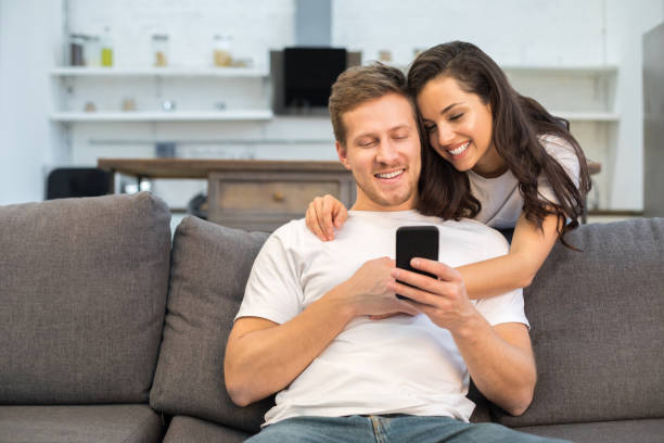 istock Happy young couple using smartphone in their living room 1209490463