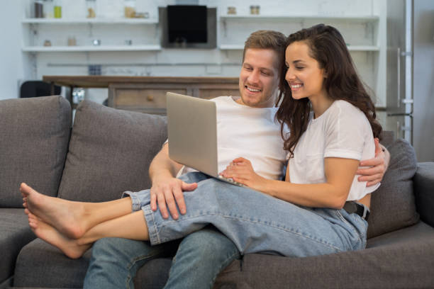 istock Smiling young couple looking at gadget screen at home 1209492015