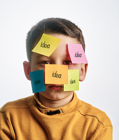 Cute child on white background. There is adhesive notes on his face.