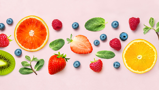 Fruit and berry pattern of various ripe berries and mint on pink background. Top view