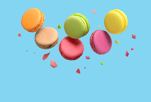 Traditional french multicolored macaroons falling on blue background