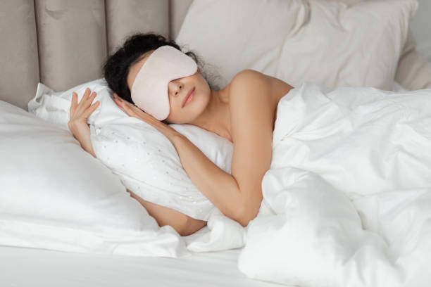 istock Beautiful woman sleeping seeing dreams in mask on white pillow 1209505259