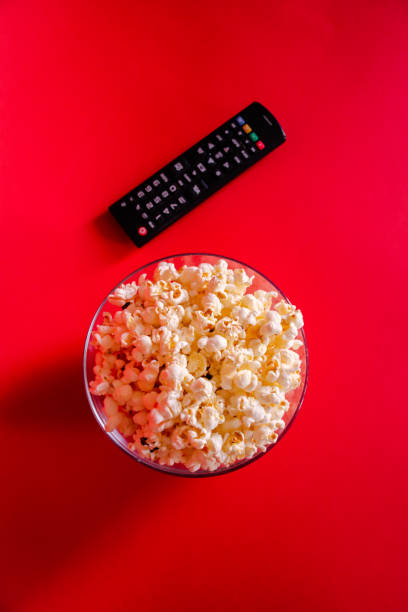 istock From above fresh popcorn in a bow next to a remote control on a red background 1209506564