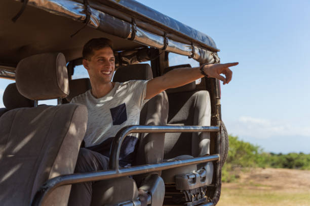 istock young man pointing wildlife from a safari jeep 1209509850