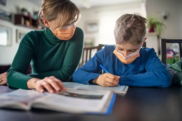 Mother and little boy wearing face masks. The mother is homeschooling her son during a virus outbreak.
Nikon D850