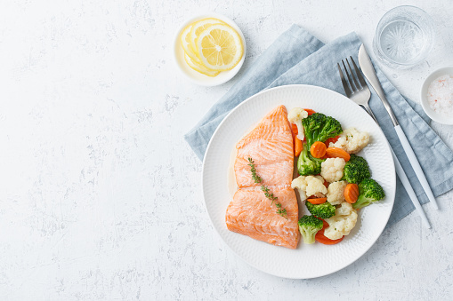 Steam salmon and vegetables, Paleo, keto, fodmap, dash diet. Mediterranean diet with steamed fish. Healthy concept, white plate on gray table, gluten free, lectine free, top view, copy space