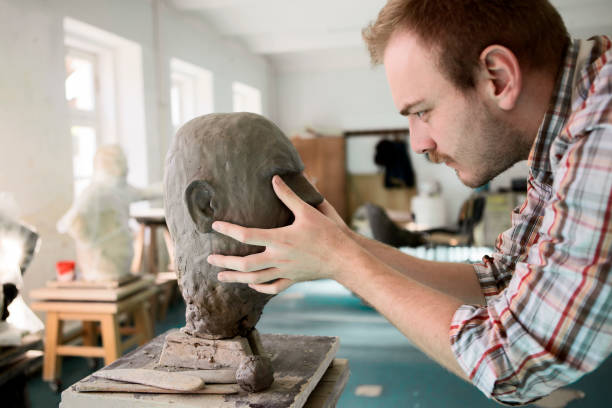 istock Sculptor working on his clay head sculpture ,sculpting a face 1209522739