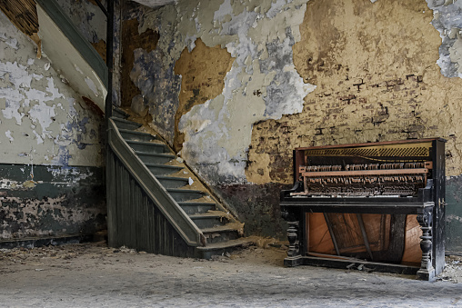 Piano by a staircase in an old decayed room