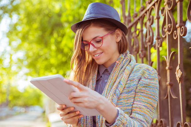 istock Happy young woman using tablet computer outdoors 1209525136