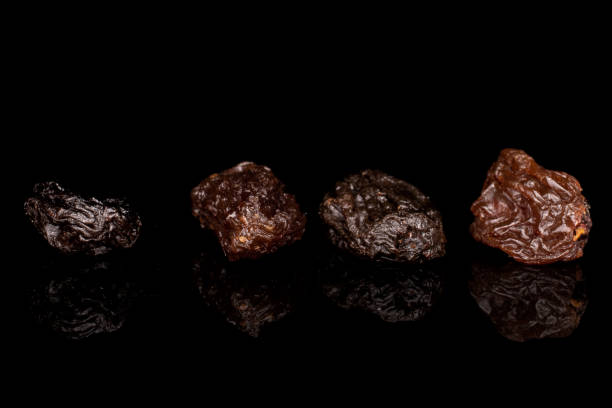 Dried dark raisin isolated on black glass