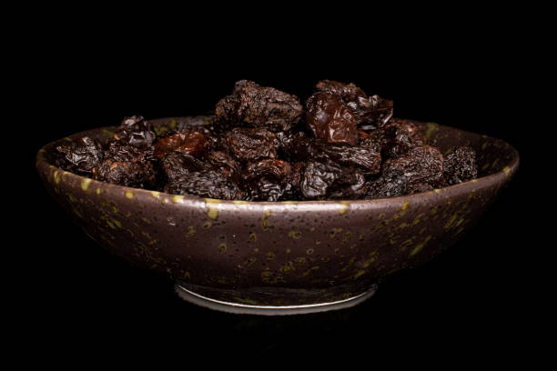 istock Dried dark raisin isolated on black glass 1209526822