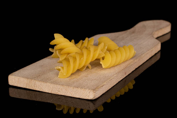 istock Yellow fusilli pasta isolated on black glass 1209529349