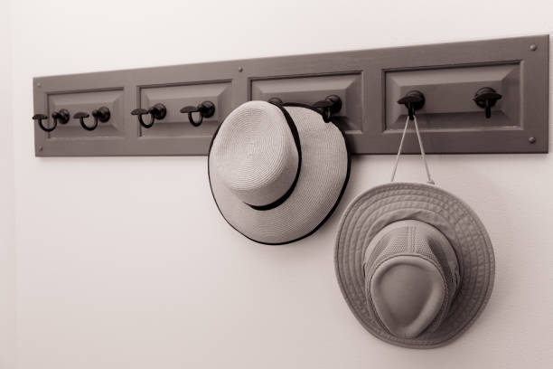 istock Sepia image of a man's and woman's hat hanging on hooks 1209535525