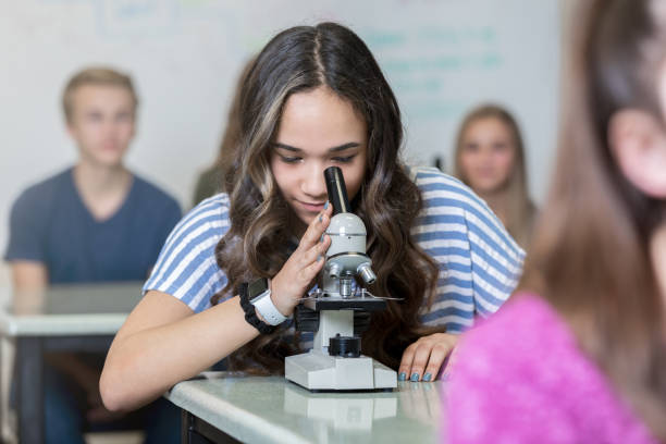 istock Teenage high school student looking into microscope in science class 1209545807