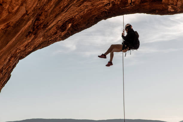 escalador de roca macho colgando en arco natural - rápel fotografías e imágenes de stock