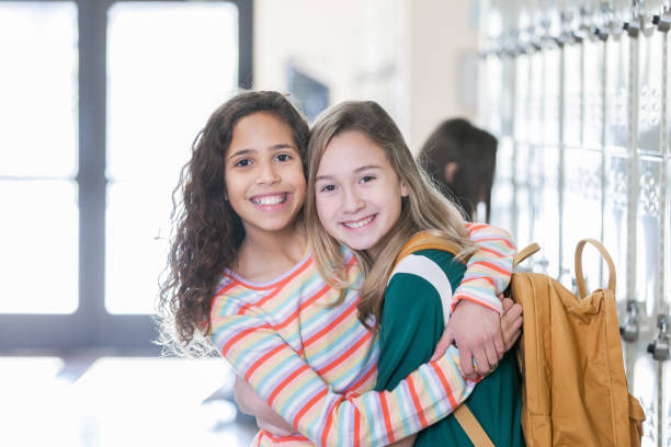 istock Female elementary age student embraces friend in school hallway 1209551665