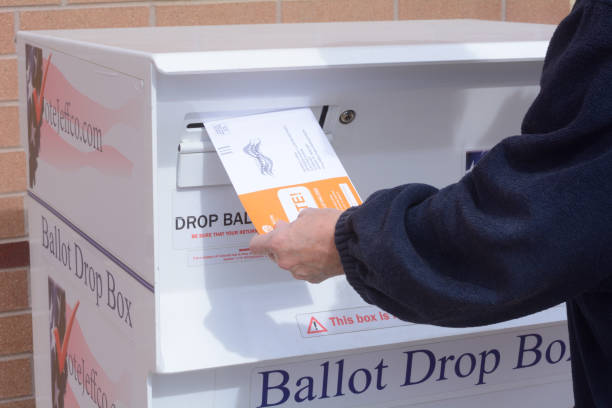 Hand putting ballot envelope into Jefferson County Colorado ballot drop box Hand putting Jefferson County Colorado election ballot envelope into ballot drop box in early voting mail election primary election photos stock pictures, royalty-free photos & images