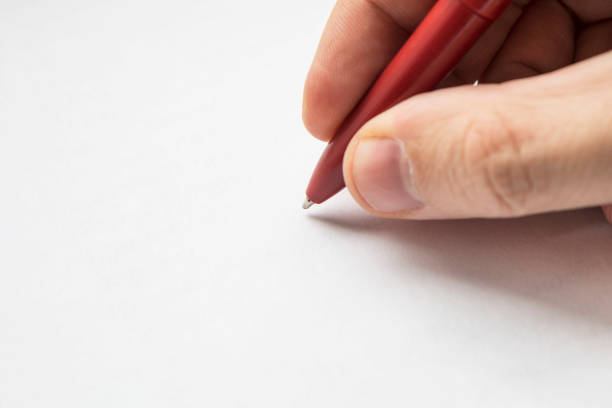 istock Red pen in hands close up. right hand with pencil and left empty over a white blank sheet of paper lying on table. empty space for design 1209552379