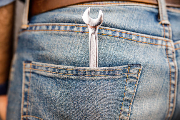 Close up of man is keeping hand instrument in denim trousers. Isolated on grey background