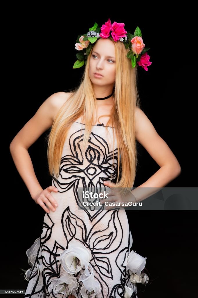 Fashionable Blonde Woman in Floral Crown Standing Against Black Background with Hands on Hip - stock photo Fashionable Blonde Woman in Floral Crown Standing Against Black Background with Hands on Hip Floral Crown Stock Photo