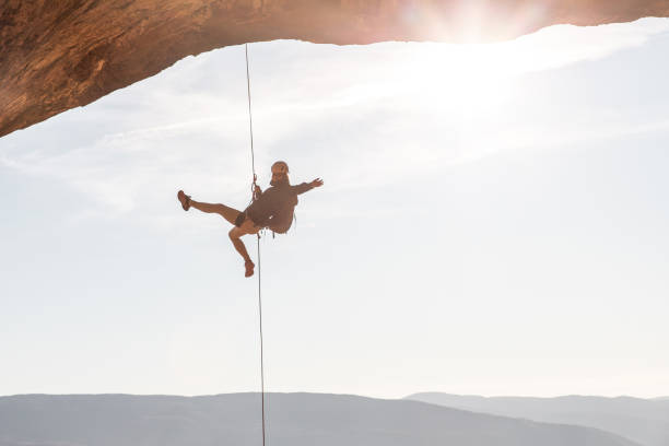 istock Male rock climber hanging on natural arch 1209560164