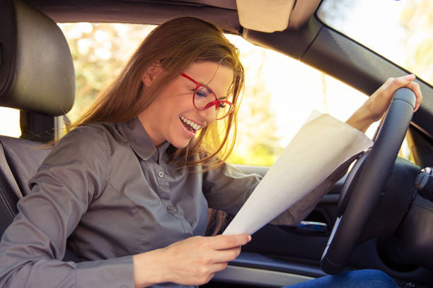 istock Excited woman in car reading papers 1209560311