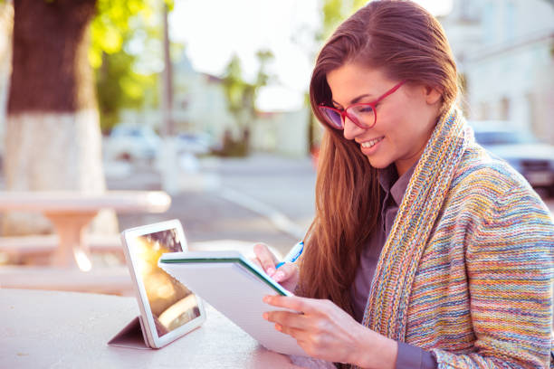 Happy woman with pencil writing in notebook working outdoor