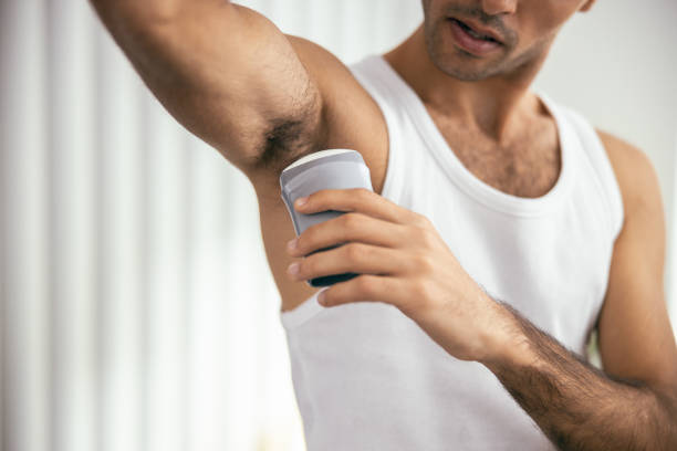 handsome guy in t-shirt using deodorant in room - shirt lifestyles close up cheerful imagens e fotografias de stock