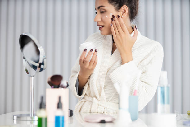 istock Smiling beautiful young female oman is using cream at home 1209569452
