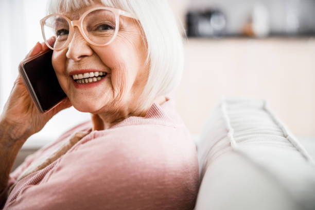 istock Cheerful old lady in glasses talking on cellphone 1209575214