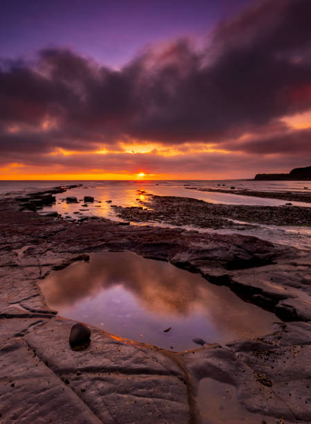istock Kimmeridge sunset - rain clouds clear to reveal red skies 1209576150