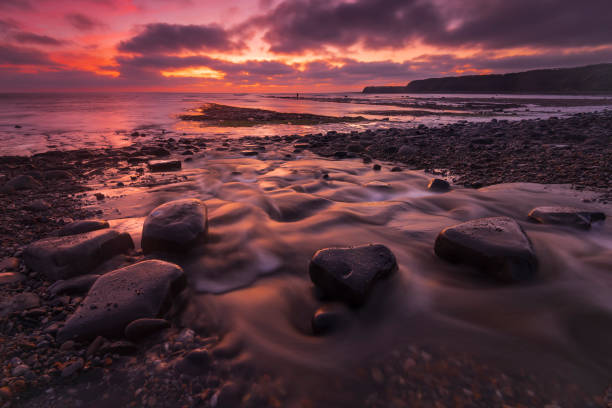 istock Kimmeridge sunset - rain clouds clear to reveal red skies 1209576178