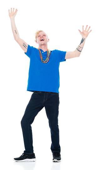 Front view of aged 20-29 years old with blond hair caucasian male standing in front of white background wearing necklace who is laughing