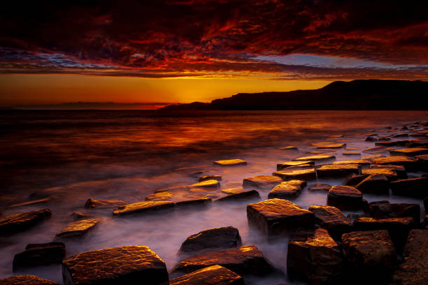 istock Kimmeridge sunset - rain clouds clear to reveal red skies 1209580501