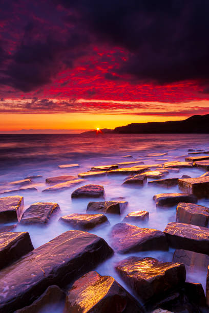 istock Kimmeridge sunset - rain clouds clear to reveal red skies 1209581270
