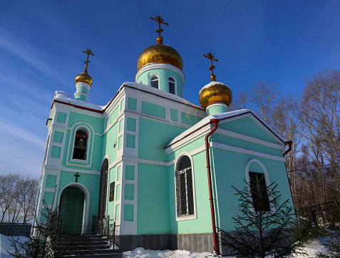 Beautiful Russian temple with golden domes and crosses on a background of blue sky in a winter sunny day.