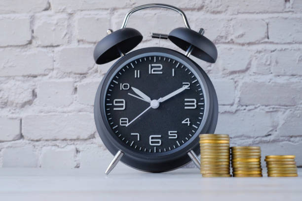 Close up of alarm clock and stack of coin on table