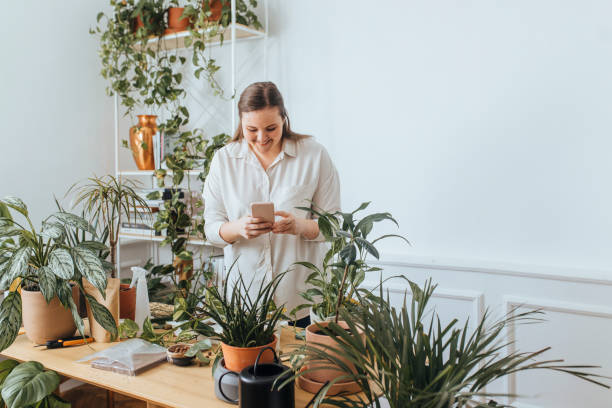 istock Smiling Plus Size Caucasian Woman Using Her Smartphone While Gardening at Home 1209589010